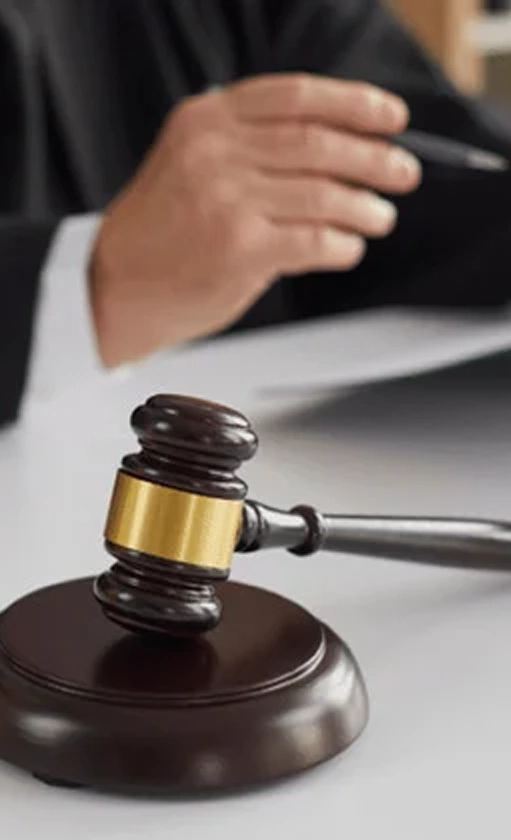 Close-up of a gavel and hand writing on legal documents